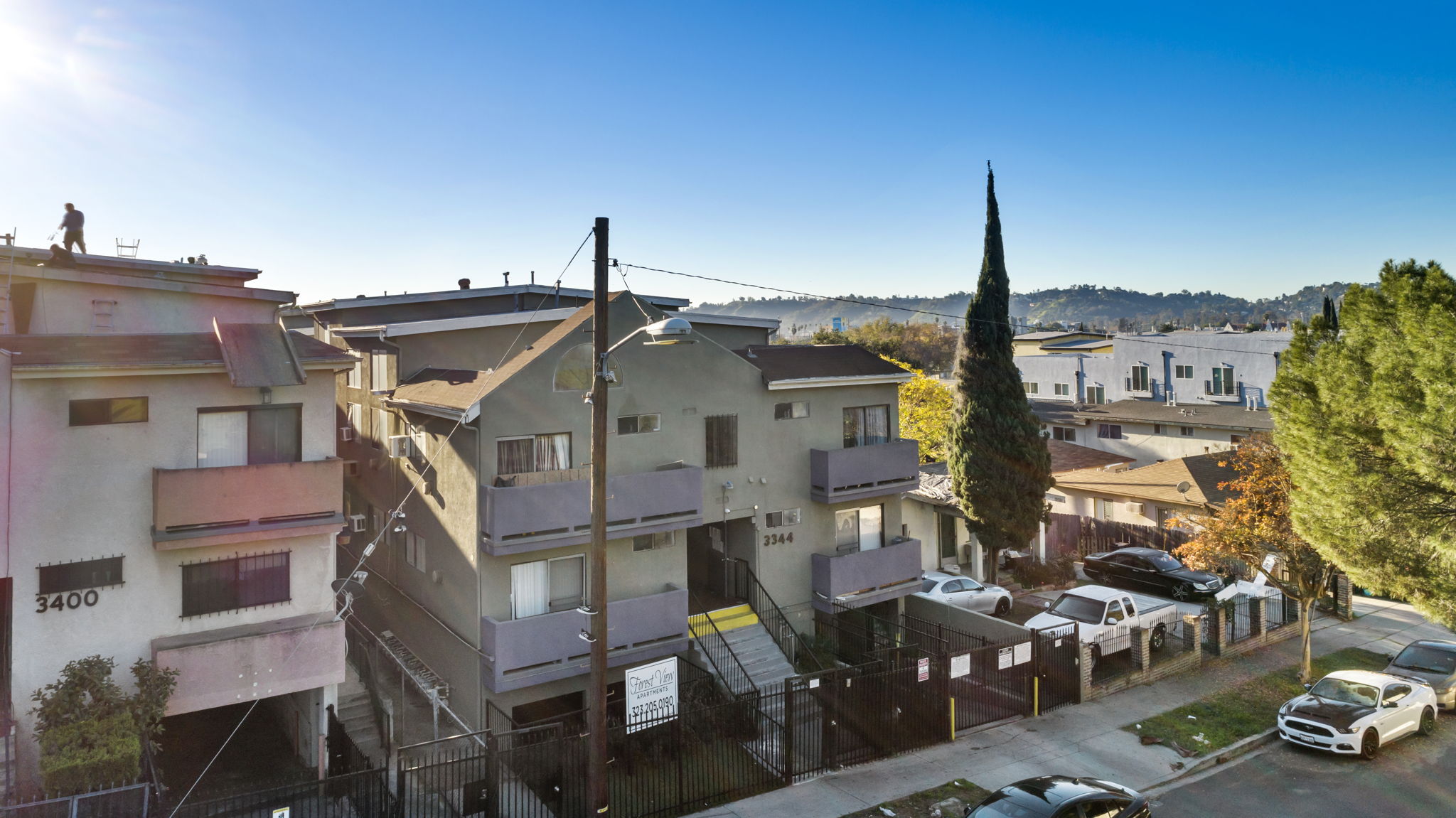 A sunny day in a residential area with cars parked on the street.